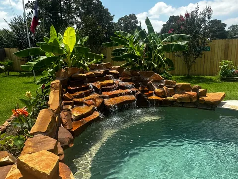 Rock waterfall flowing into a pool beside tropical plants