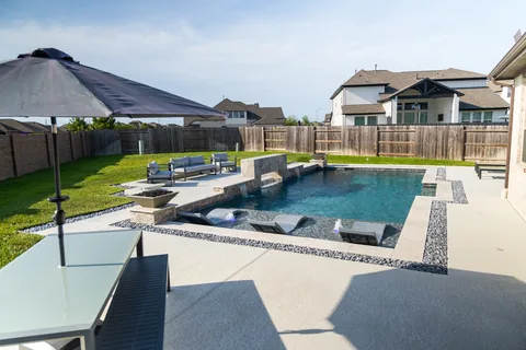 Custom backyard pool with lounge chairs, water features, and poolside seating