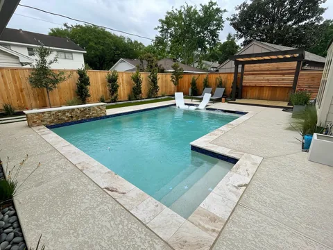 Backyard pool with in-water loungers and a pergola